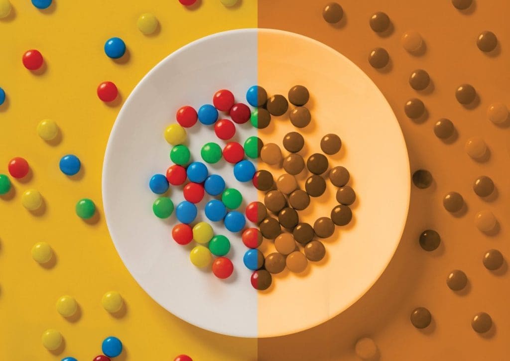 split screen of m&ms on a white plate one with a yellow background the other orange